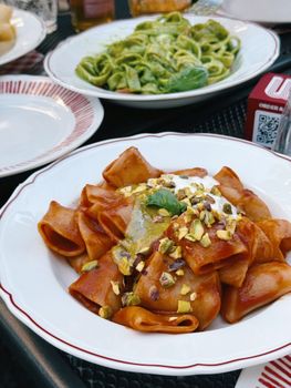 A variety of Italian pasta dishes served outdoors in Milan, Italy, showcasing rich flavors and textures.