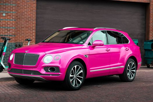 Bright pink SUV with sleek design parked on an urban street.