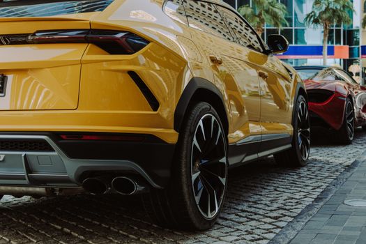 Close-up of a yellow Lamborghini Urus parked on a cobblestone street in Dubai.