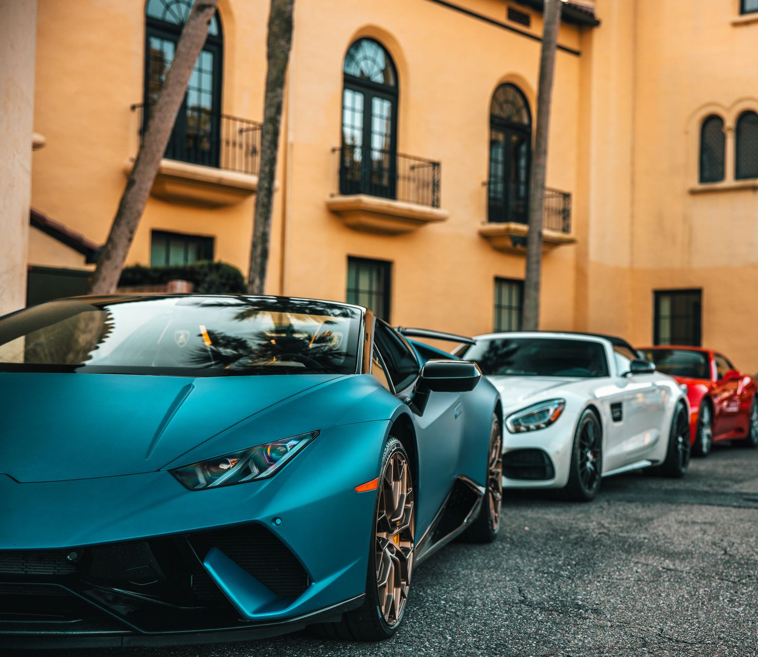 A row of luxury sports cars including a Lamborghini parked on a city street in Jacksonville.